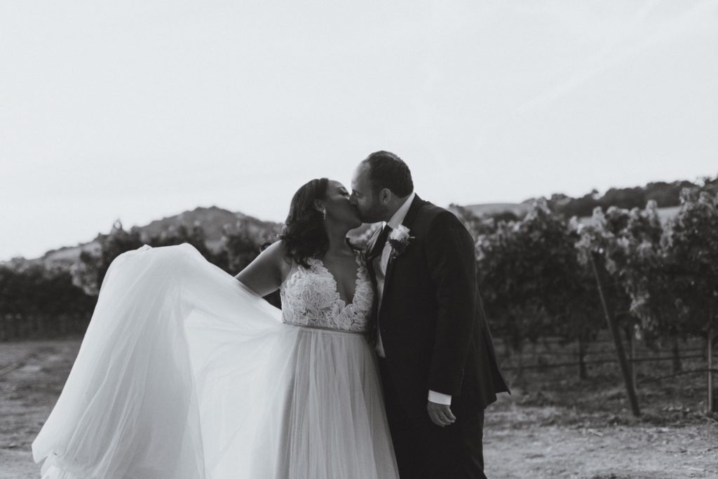 bride and groom kissing in santa barbara vineyard