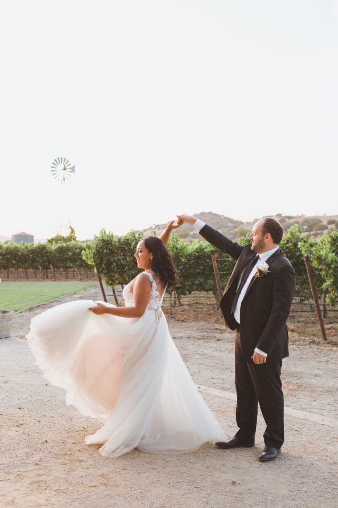 groom twirling bride in a vineyard