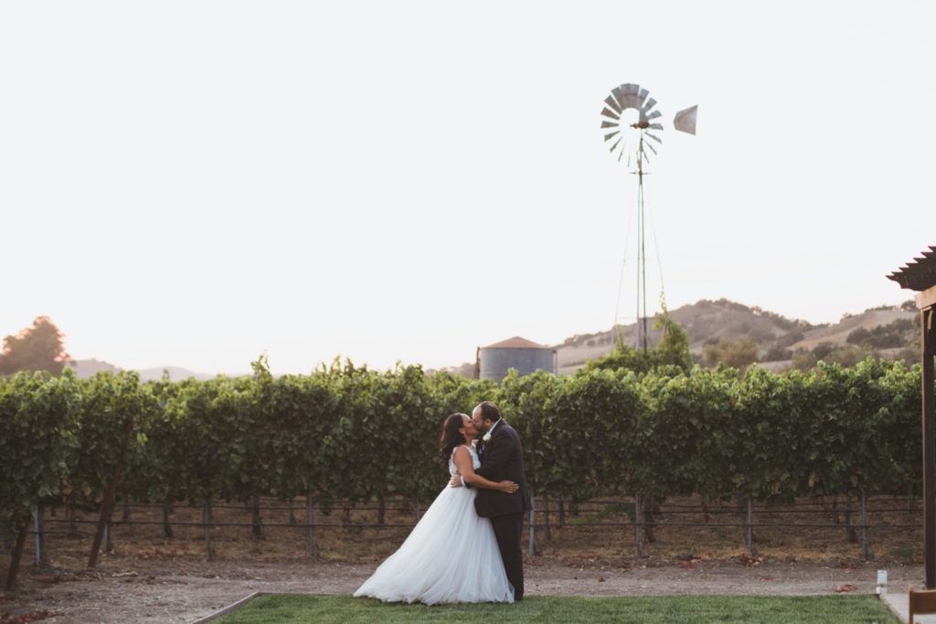 bride and groom kissing in vineyard