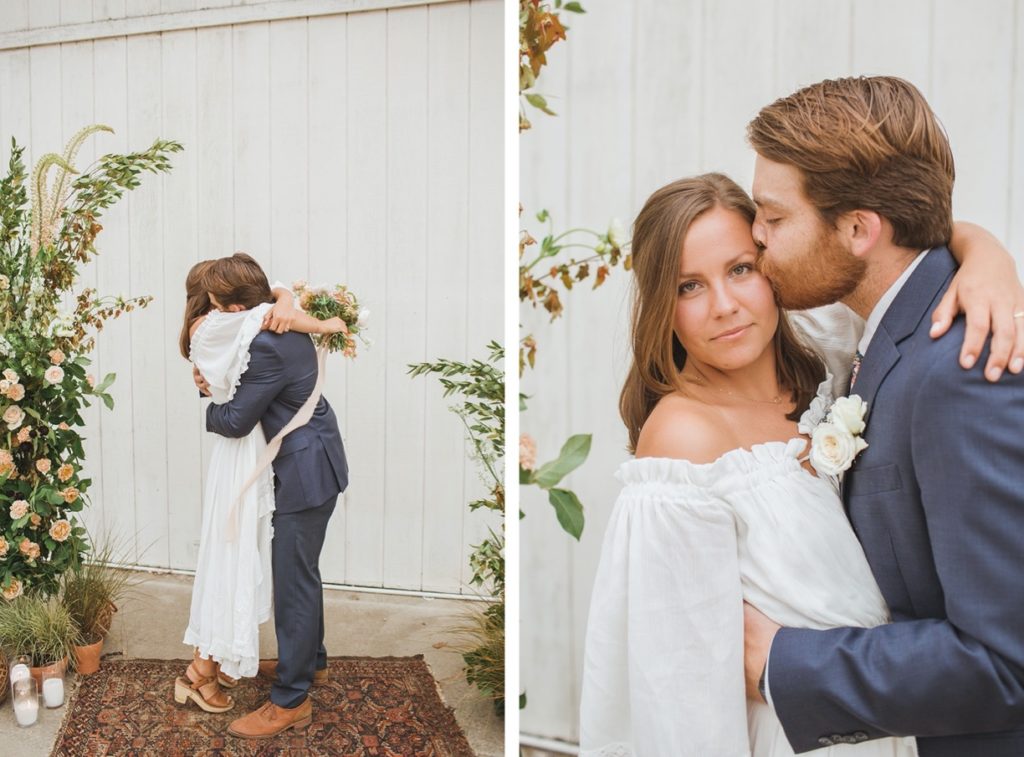 couple hugging under ceremony floral arch