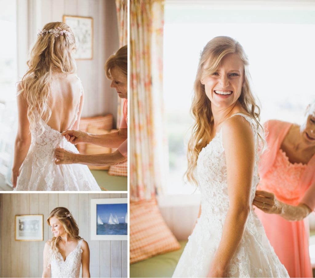 bride laughing while putting on dress in beach house